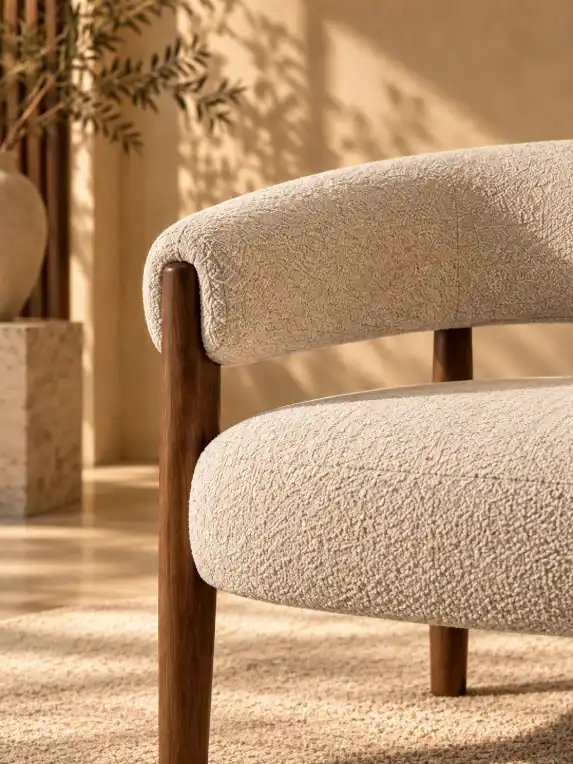 Close-up view of a chair showing its natural texture and upholstery details in a warm luxury interior with soft golden sunlight.