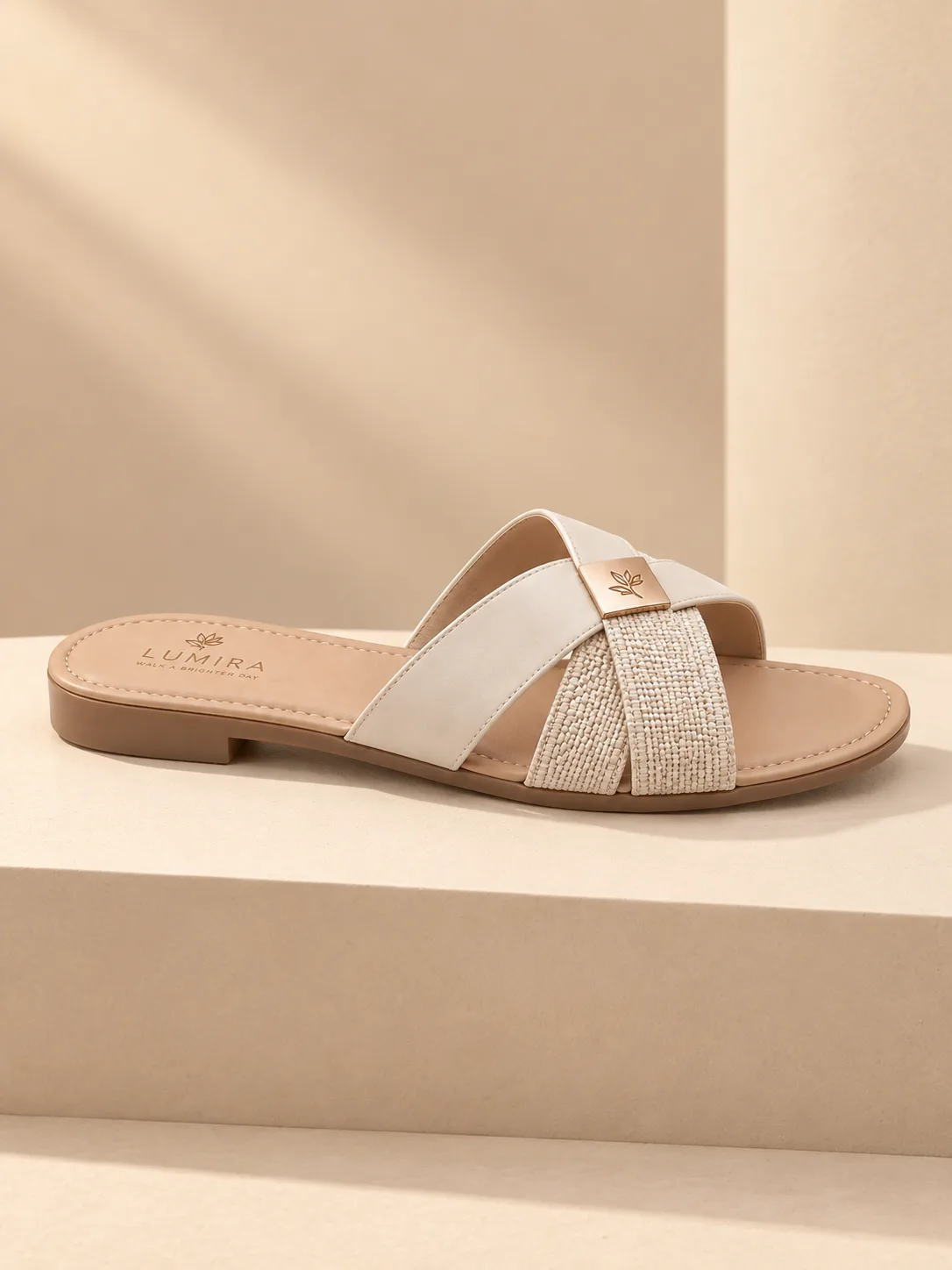 Single women’s sandal shown in a clean side profile on a warm beige pedestal with soft sunlight and elegant luxury product photography styling.