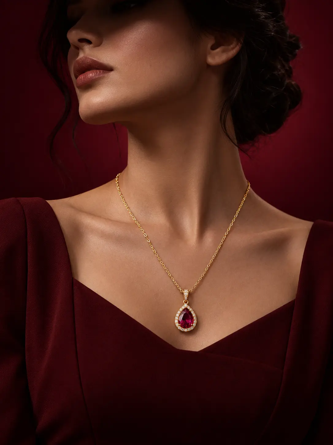 Elegant female AI model wearing a gold necklace with a ruby teardrop pendant against a deep burgundy luxury studio background.